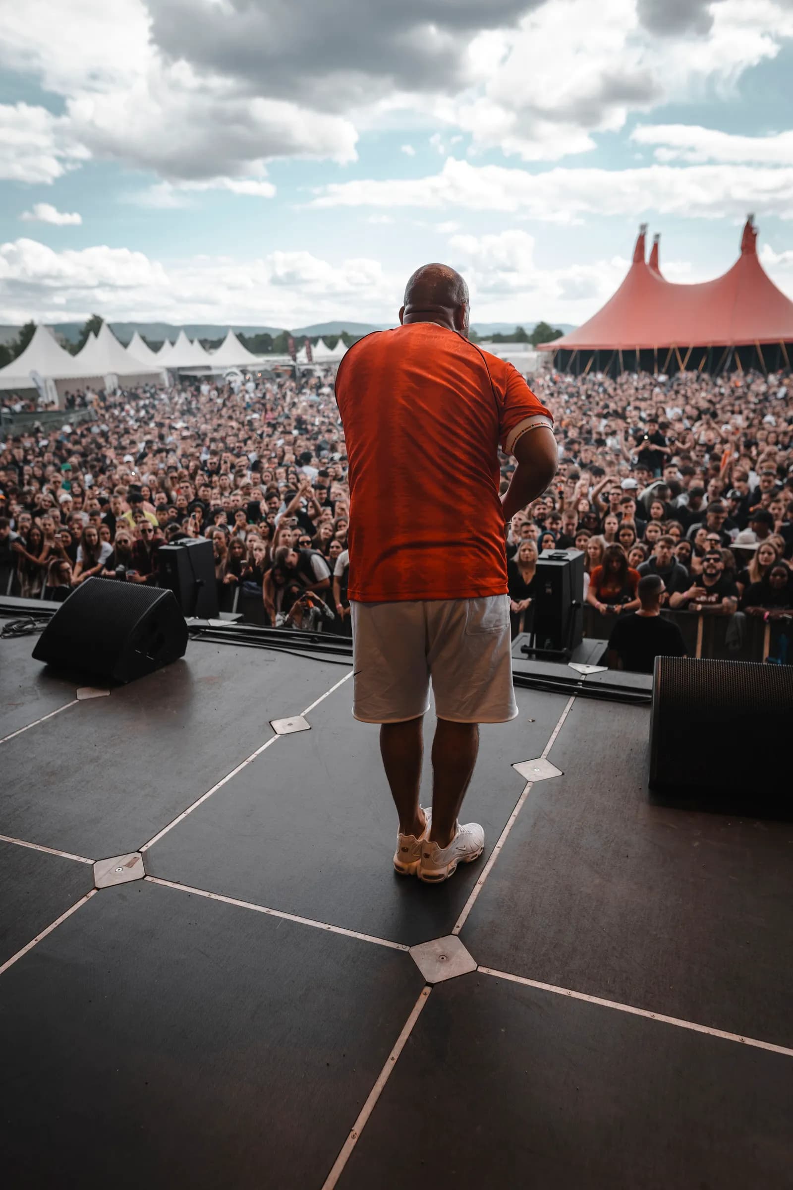Künstler von hinten auf der Open-Air-Bühne, davor dichte Menschenmenge und Festivalzelte.