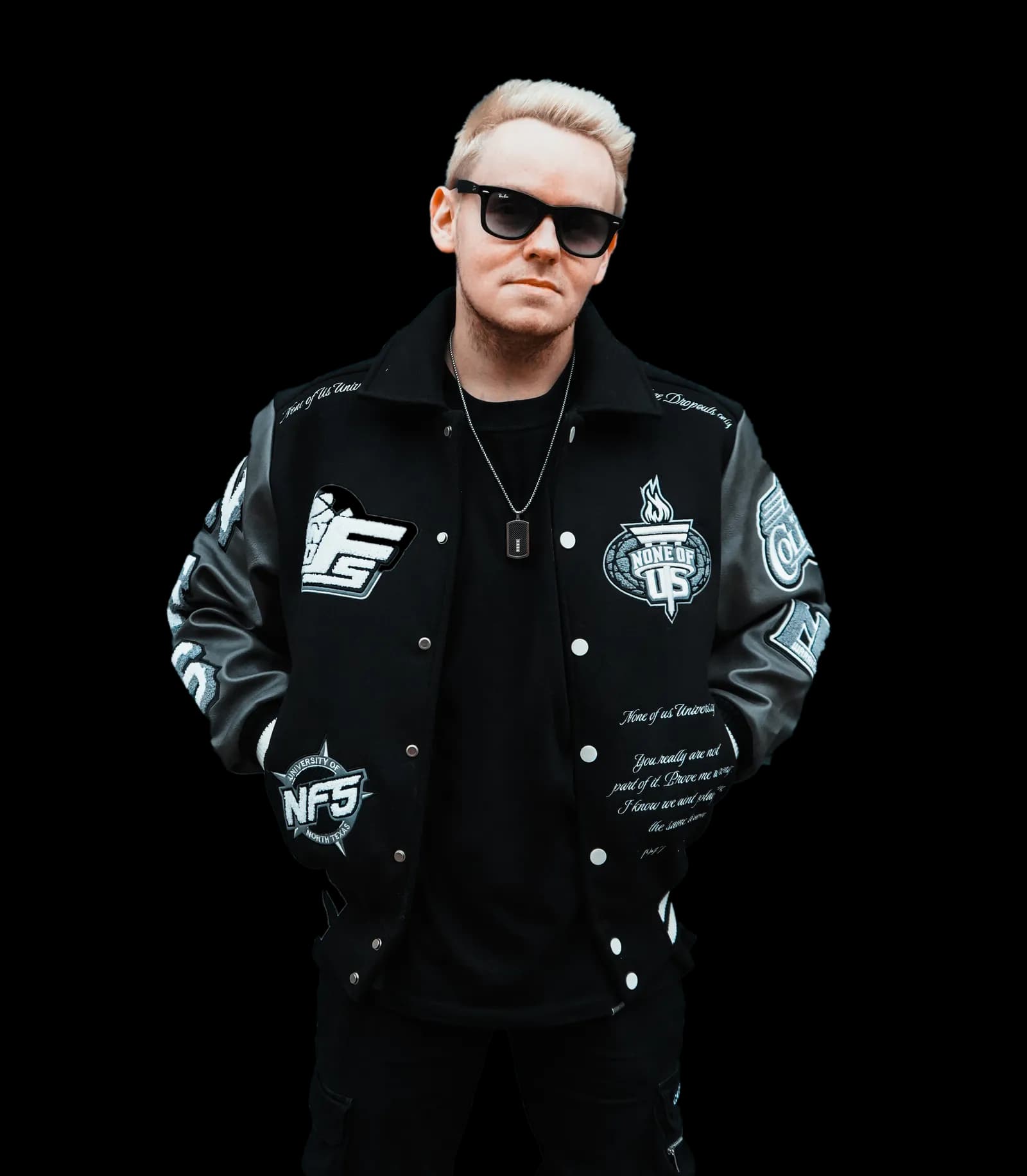 Tim Twice in schwarzer College-Jacke mit Aufnähern und Sonnenbrille, freigestellt.